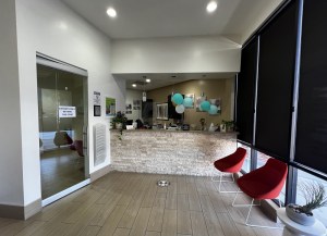 Entrance to dental clinic with glass door, red chairs, and balloon decor