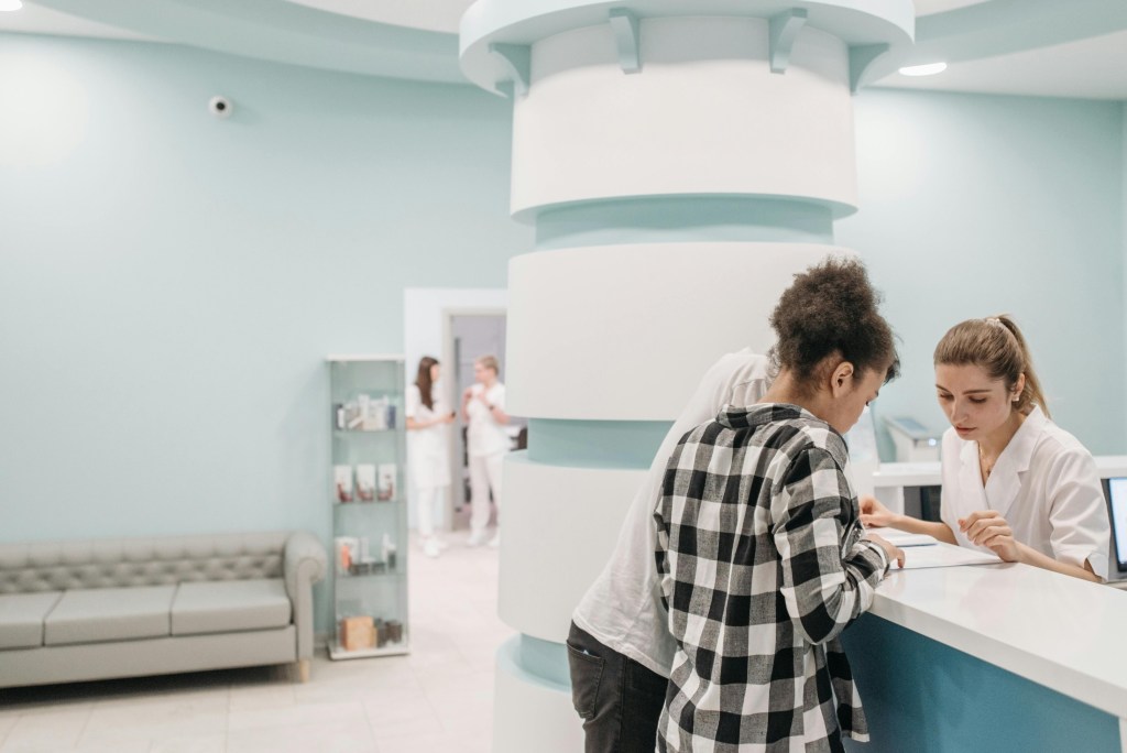 Patient checking in at dental clinic front desk with staff member