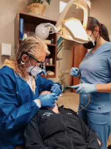 Dentist and assistant treating patient under bright dental light
