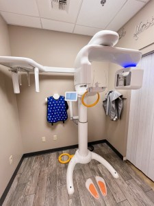 Dental imaging room with 3D scanner and safety gear on wall