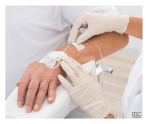 Nurse placing IV catheter in patient&rsquo;s arm &mdash; IDC logo visible