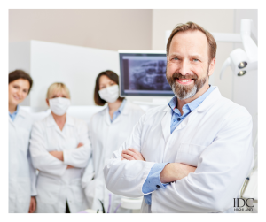 Dental team smiling confidently in clinic, X-ray screen behind